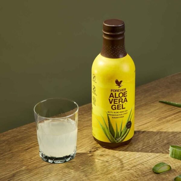 Botella de Forever Aloe Vera Gel junto a un vaso servido sobre una mesa