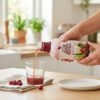Mano sirviendo Forever Aloe Berry Nectar en un vaso