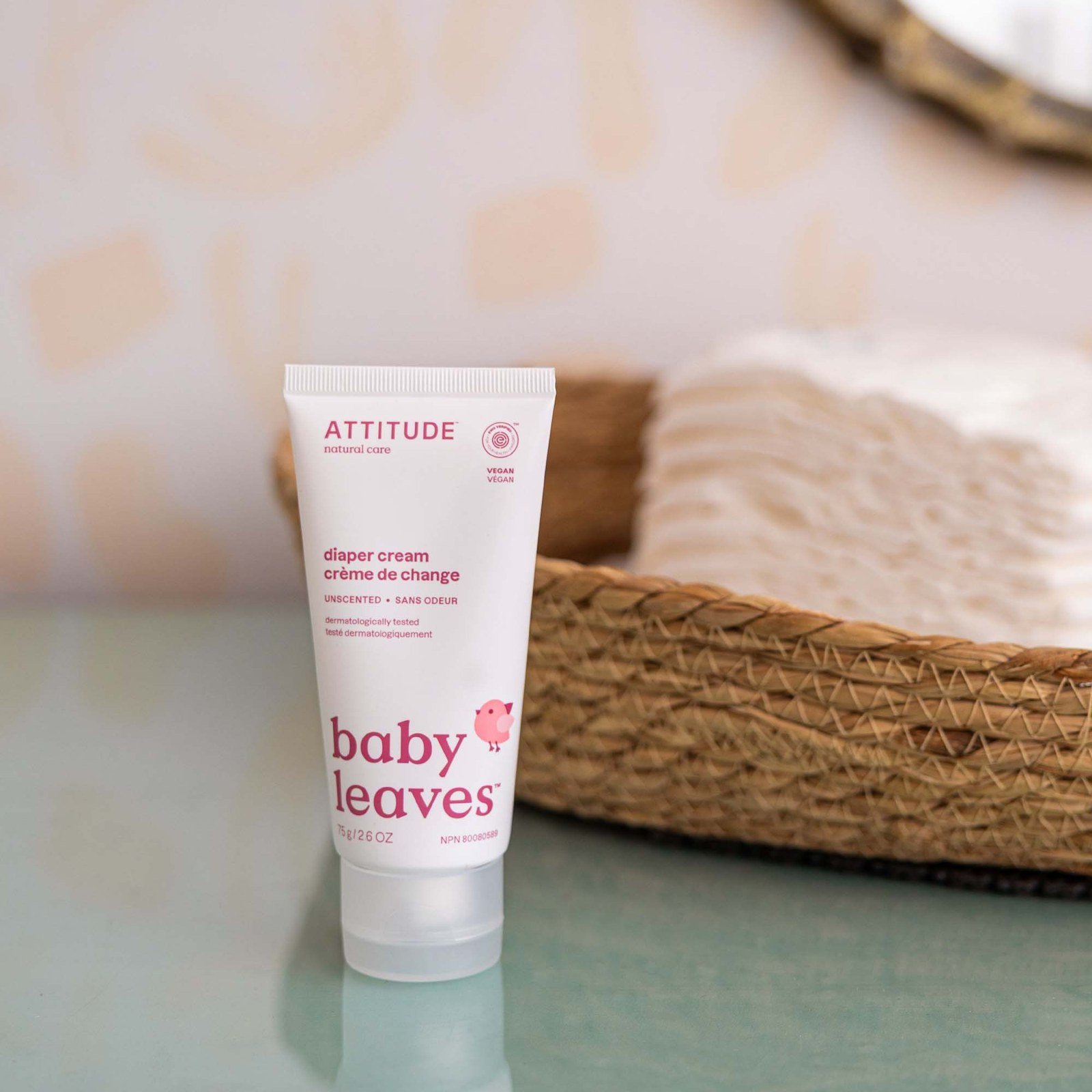Tubo de crema para escaldaduras ATTITUDE baby leaves junto a pañales en el cambiador